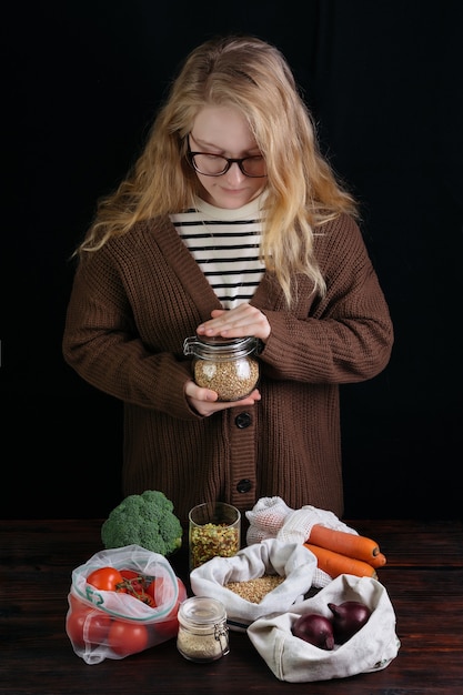 Femme tenant une banque réutilisable avec des céréales sur des aliments biologiques