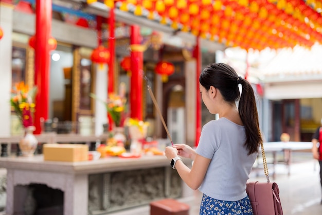 Femme tenant des bâtons d'encens en train de fumer dans un temple chinois