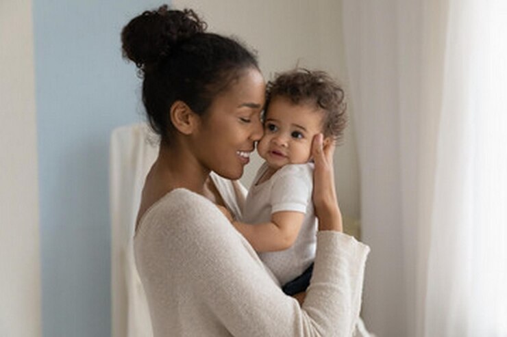 Photo une femme tenant un bébé et portant une chemise blanche