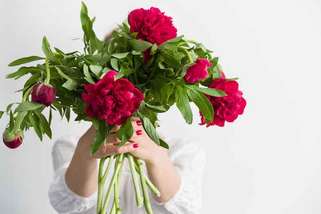 Femme tenant de belles pivoines rouges