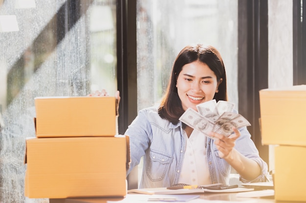 femme tenant des billets d&#39;argent sourit avec plaisir.