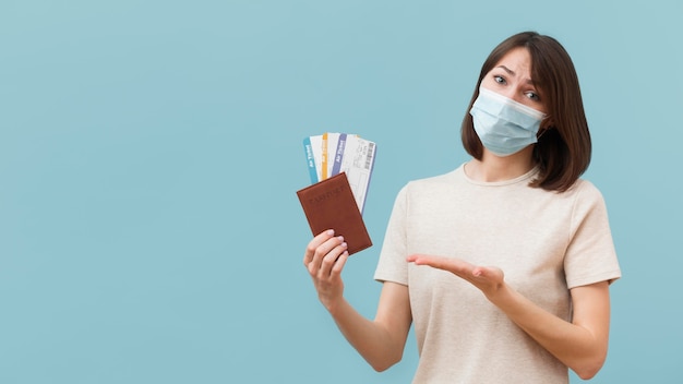 Femme tenant des billets d'avion tout en portant un masque médical