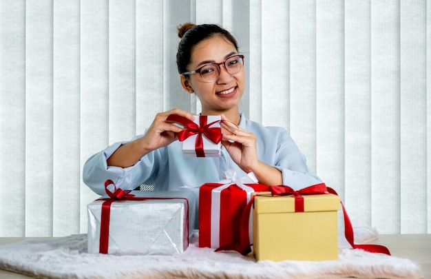 Femme tenant une boîte cadeau blanche attachée avec un ruban rouge présent pour le festival de donner des vacances spéciales.