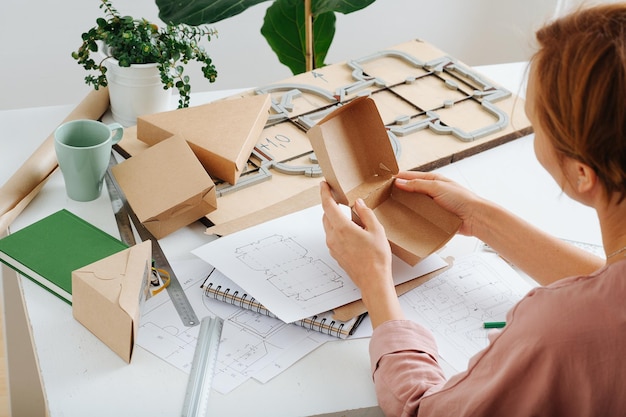 Femme tenant une boîte dans les mains processus de réflexion sur les moyens de l'améliorer