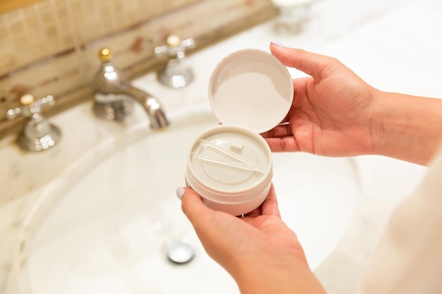 Femme tenant et boîte ouverte avec des patchs oculaires hydrogel dans la salle de bain Concept de spa du matin