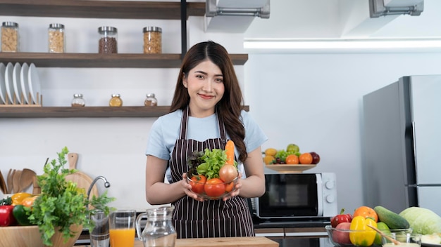 Une femme tenant un bol de légumes dans une cuisine