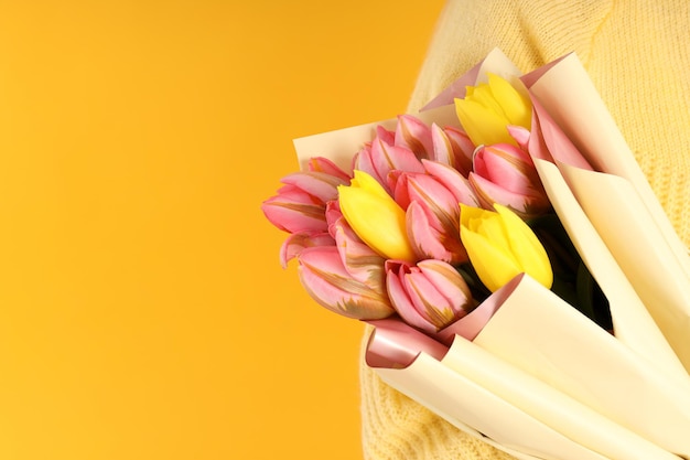 Femme tenant un bouquet de fleurs sur fond jaune