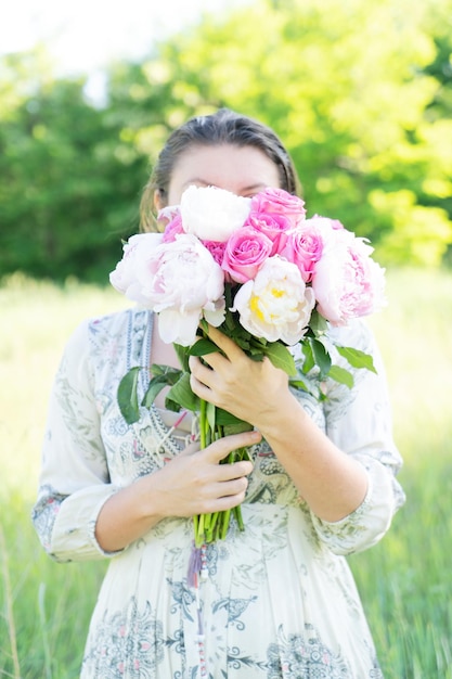 Femme tenant un bouquet de pivoines et de roses fraîches