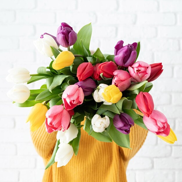 une femme tenant un bouquet de tulipes devant son visage