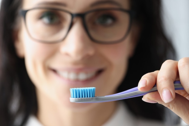 Femme tenant la brosse à dents dans ses mains gros plan. Concept de soins bucco-dentaires quotidiens