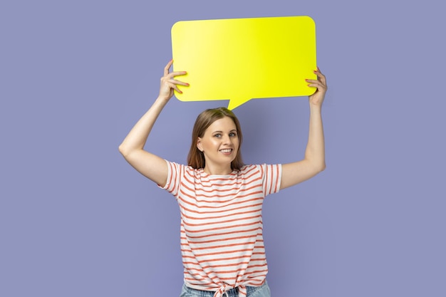 Femme tenant une bulle jaune pour le texte en regardant la caméra avec un sourire à pleines dents