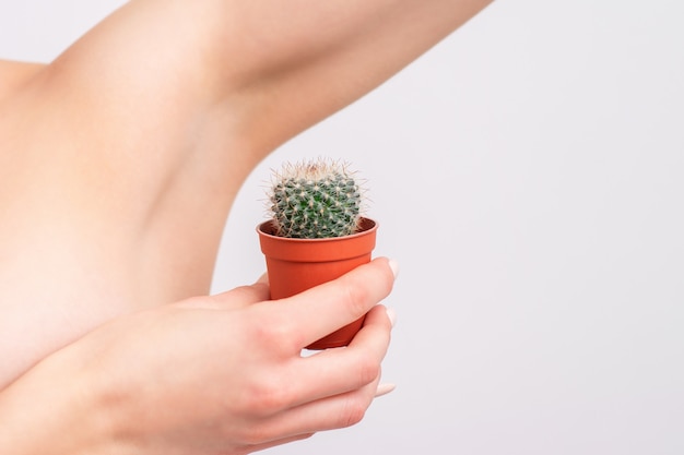 Femme tenant un cactus vert près de son aisselle.