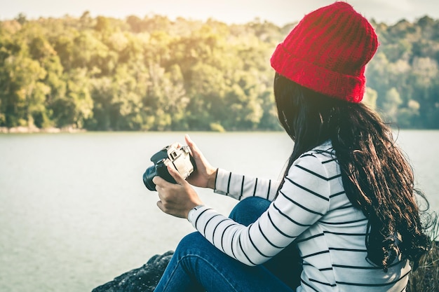 Photo femme tenant une caméra contre le lac