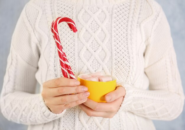 Femme tenant une canne en bonbon de Noël et une tasse dans les mains