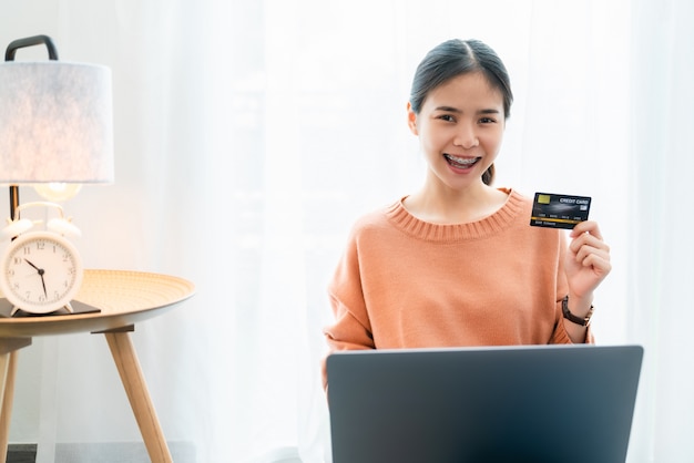 Femme tenant une carte de crédit et à l'aide d'un ordinateur portable numérique