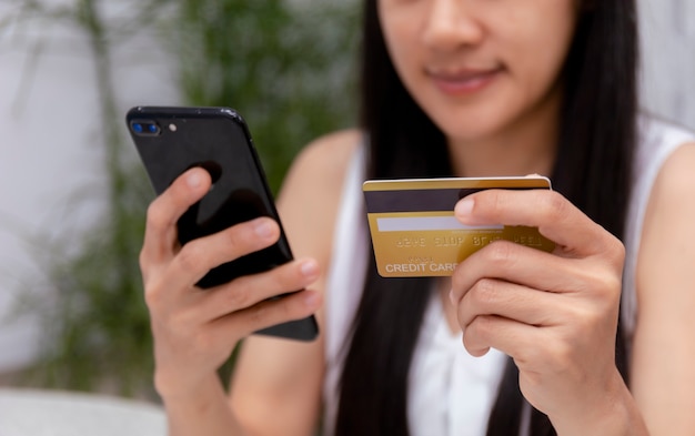 Femme tenant une carte de crédit et à l'aide de téléphone mobile