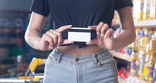 Femme tenant une carte de crédit au supermarché.