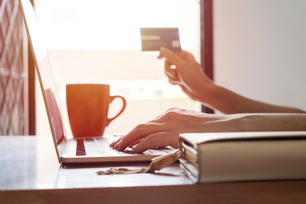 Femme tenant une carte de crédit et utilisant un ordinateur portable