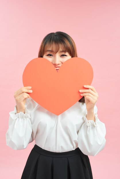 Femme tenant une carte en forme de coeur en papier