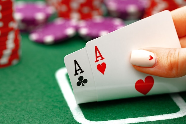 Femme tenant des cartes à jouer au poker à table verte