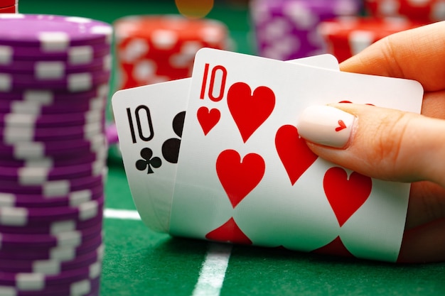 Femme tenant des cartes à jouer au poker à table verte