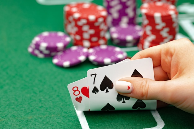 Femme tenant des cartes à jouer au poker à table verte