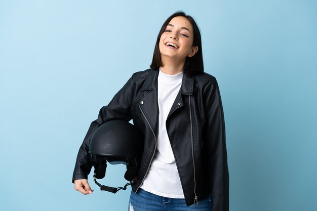 Femme tenant un casque de moto isolé sur bleu en riant