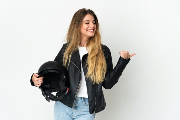 Femme tenant un casque de moto posant isolé contre le mur blanc