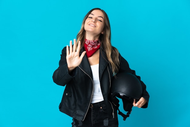 Femme tenant un casque de moto posant isolé contre le mur blanc