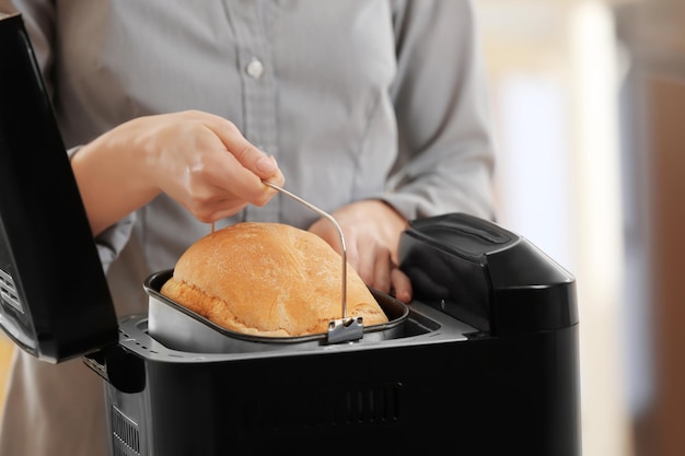 Femme tenant une casserole de machine à pain avec du pain frais