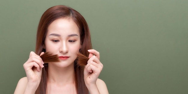 Femme tenant les cheveux abîmés la main et regardant