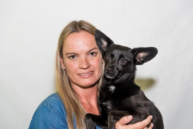 Une femme tenant un chien noir dans ses bras toilettage de chien d'adoption