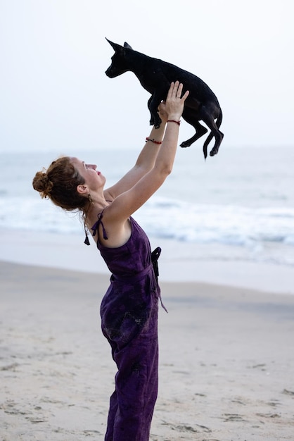 Une femme tenant un chien sur une plage