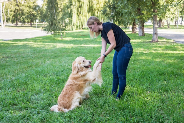 Femme tenant un chien retriever par les pattes avant dans le parc