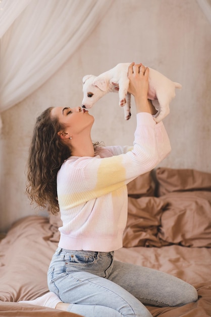 Femme tenant un chiot jouant dans son lit à la maison se bouchent. Relation amicale. Joie.