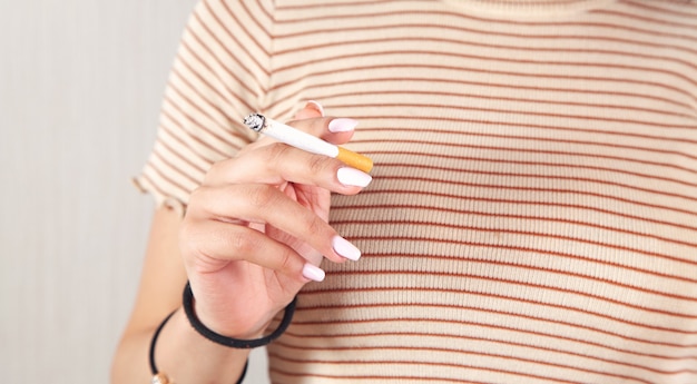 Femme tenant une cigarette allumée. Fumeur