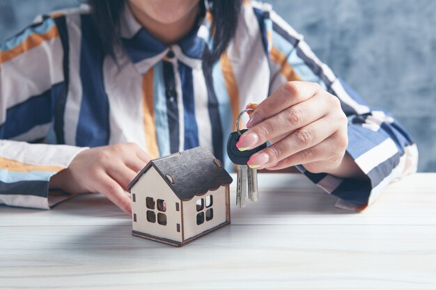 Femme tenant des clés et maison sur table