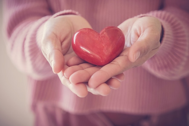 Femme tenant un coeur rouge, assurance maladie, concept de don, journée mondiale de la santé mentale, journée mondiale du cœur