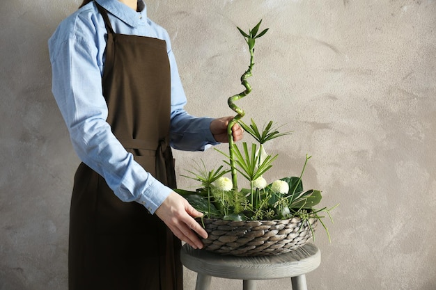 Femme tenant une composition florale sur un fond de couleur