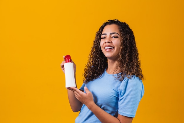 Femme tenant une crème sur fond jaune