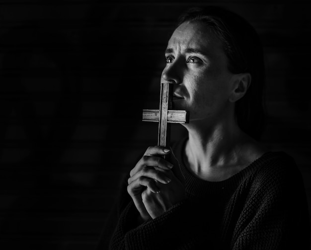 Femme tenant une croix priant pour Dieu