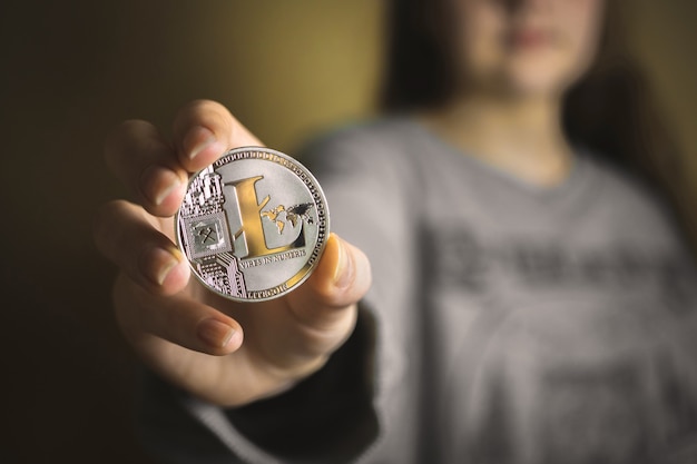 Femme tenant une crypto-monnaie litecoin physique dans sa main, photo en gros plan