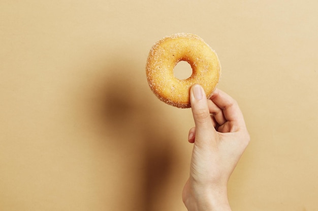 Femme tenant un délicieux beignet sur fond de couleur