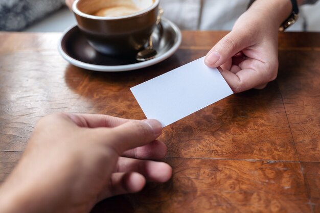 Une femme tenant et donnant une carte de visite vide à quelqu'un