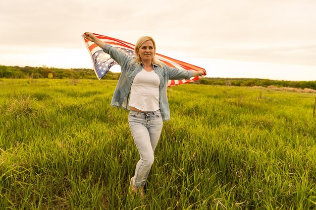 Femme tenant le drapeau américain à l'extérieur sur un pré. 4 juillet - Jour de l'Indépendance.