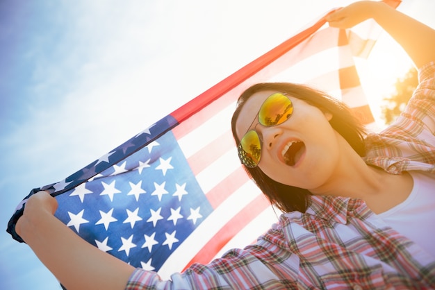 Femme tenant le drapeau des États-Unis d&#39;Amérique et courir sur la plage.