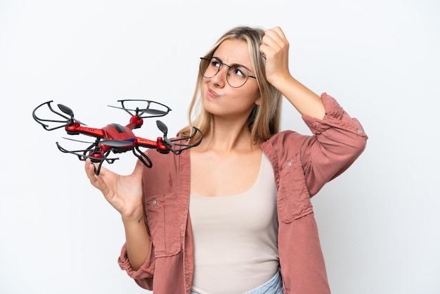 Femme tenant un drone sur fond isolé ayant des doutes et avec une expression de visage confuse