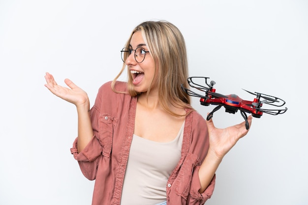 Femme tenant un drone sur fond isolé avec une expression faciale surprise