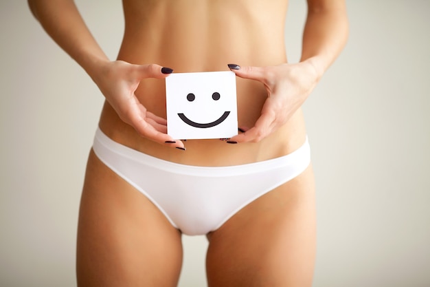 Femme tenant du papier avec une marque de sourire sur son ventre