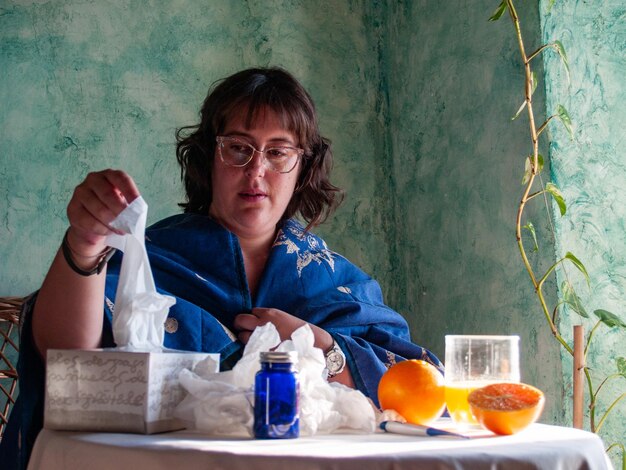 Femme tenant du papier tissu par des oranges sur la table à la maison